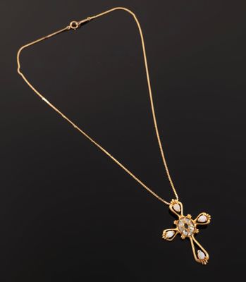 a gold necklace with a cross pendant on a black background