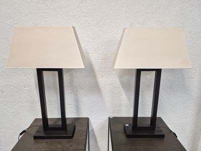 une paire de lampes de table en métal noir avec des abat-jours blancs