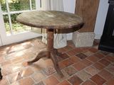 une petite table avec un plateau en bois posée sur un sol en briques