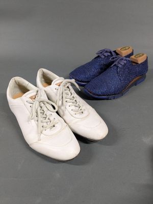 two pairs of white shoes are lined up on a gray surface