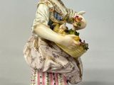 a figurine of a woman holding a basket of flowers