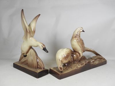 two figurines of birds sitting on top of each other on a table