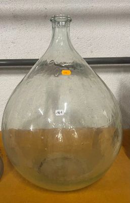 un grand vase en verre posé sur une table, à côté d'une bouteille contenant un liquide