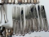 a lot of silver knives and spoons on the table
