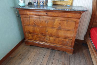 une commode en bois avec un plateau en marbre dans une chambre