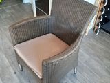 a wicker chair with a cushion on it in a room
