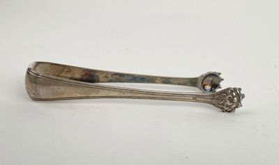 an old silver spoon with a handle sitting on top of a white table