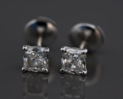 une paire de boucles d'oreilles en diamant posées sur une surface réfléchissante
