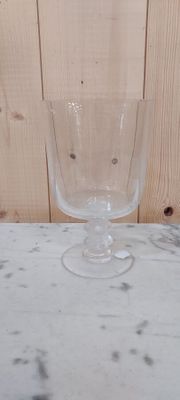 un verre à vin posé sur une table près d'un mur en bois
