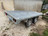 a flatbed truck that is parked in the gravel