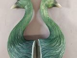 pair of green and white ceramic peacocks on a white wall