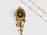 un gros plan d'un collier en or orné d'une pierre verte
