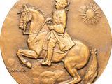 bronze medallion depicting a man riding a horse with a sun in the background