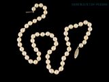 un ensemble composé d'un collier et de boucles d'oreilles en perles blanches sur fond noir