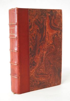 un vieux livre à la couverture rouge posé sur une surface blanche
