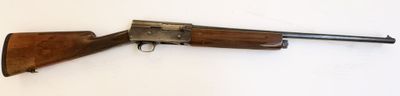 Un vieux fusil est posé sur une surface blanche, devant un fond blanc.