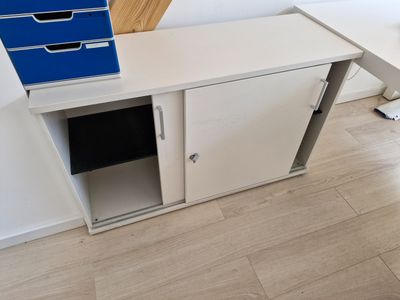 un bureau blanc sur lequel est posé un classeur bleu