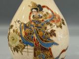 a vase with a painting on it sitting on a table