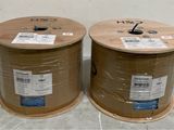 two reels of cable wrapped in plastic on the floor