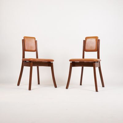 deux chaises en bois avec des assises recouvertes de cuir, sur fond blanc