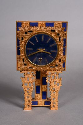 a gold clock with a blue face on a stand