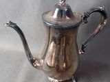 a silver tea pot on a table with a gray background