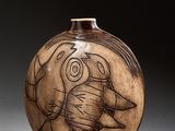 un vase marron orné d'un dessin, posé sur une table
