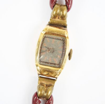 une photo d'une montre-bracelet en or avec un bracelet rouge