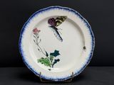 une assiette bleue et blanche décorée d'un papillon et de fleurs