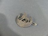 a silver pin with a horse on it sitting on a table