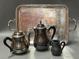 three silver teapots and a silver tray on a table