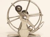 a metal spinning wheel on a stand on a white surface