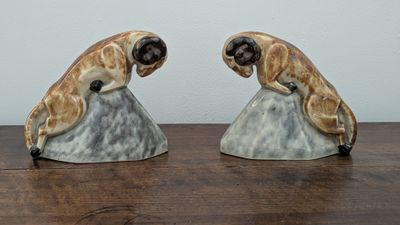 two figurines of two dogs sitting on a rock