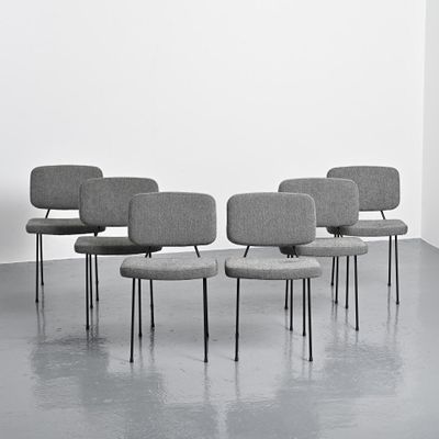 four grey chairs with black legs in a room with a white wall