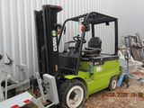 un chariot élévateur vert garé devant un immeuble