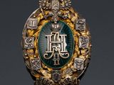an image of a gold and green broochle with a crown on it