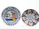 two plates with designs of birds and flowers on them on a white surface