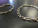 two pieces of silver bracelets on a black surface