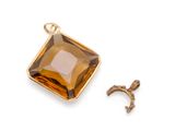 une image représentant un pendentif doré orné d'une pierre brune facettée