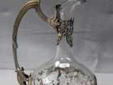 un pichet en argent et en verre posé sur une table blanche