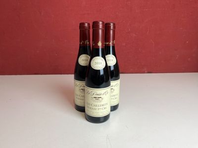 trois bouteilles de vin sont posées sur une table devant un mur rouge