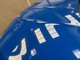 a close up of a blue sports car parked in a parking lot