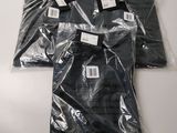 three black shirts are wrapped in plastic bags on a table