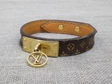 a close up of a brown leather bracelet with a gold charm