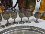 a lot of silver items on a table next to a silver pitcher