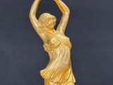 a gold statue of a woman holding a flower in her hands