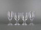 four empty wine glasses are lined up on a gray surface