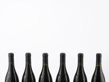 six bottles of wine are lined up in a row on a table