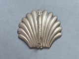 a silver shell shaped object on a blue surface