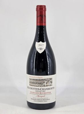 the bottle of red wine is sitting on a white surface